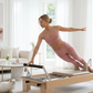 Jeune femme blonde en tenue rose faisant du pilates avec un chat à côté